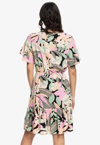 Robe fleurie à manches courtes; présente une base noire ornée de motifs roses, verts et beiges. Taille élastique et ourlet à volants.