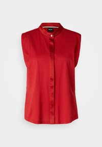 Blusa rossa senza maniche con colletto alla cinese, caratterizzata da una chiusura frontale con bottoni e una texture di tessuto liscia. Design semplice ed elegante.