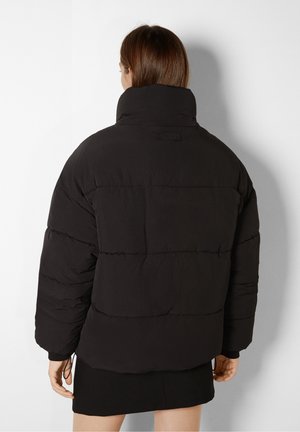 Sort pufferjakke med høj krave, oversized pasform, kviltet mønster og elastiske manchetter. Glat tekstur med et minimalistisk design.