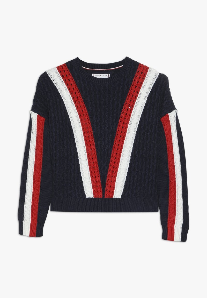 Granatowy sweter w splot kablowy z czerwonymi i białymi paskami w kształcie V na przodzie oraz pasującymi paskami na rękawach, okrągły dekolt.