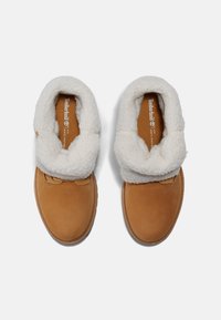 Chaussures en suede marron avec un doux col en fausse fourrure blanche. Présentent un bout arrondi et des accents cousus. Intérieur doublé avec un logo sur la semelle intérieure.