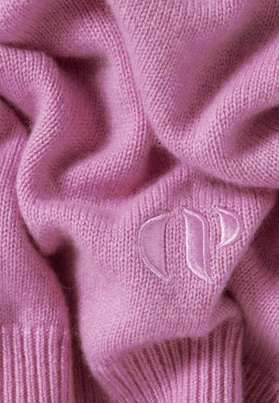 Matériau en laine tricotée rose avec une texture douce. Présente un logo brodé subtil dans le coin inférieur et un ourlet côtelé.