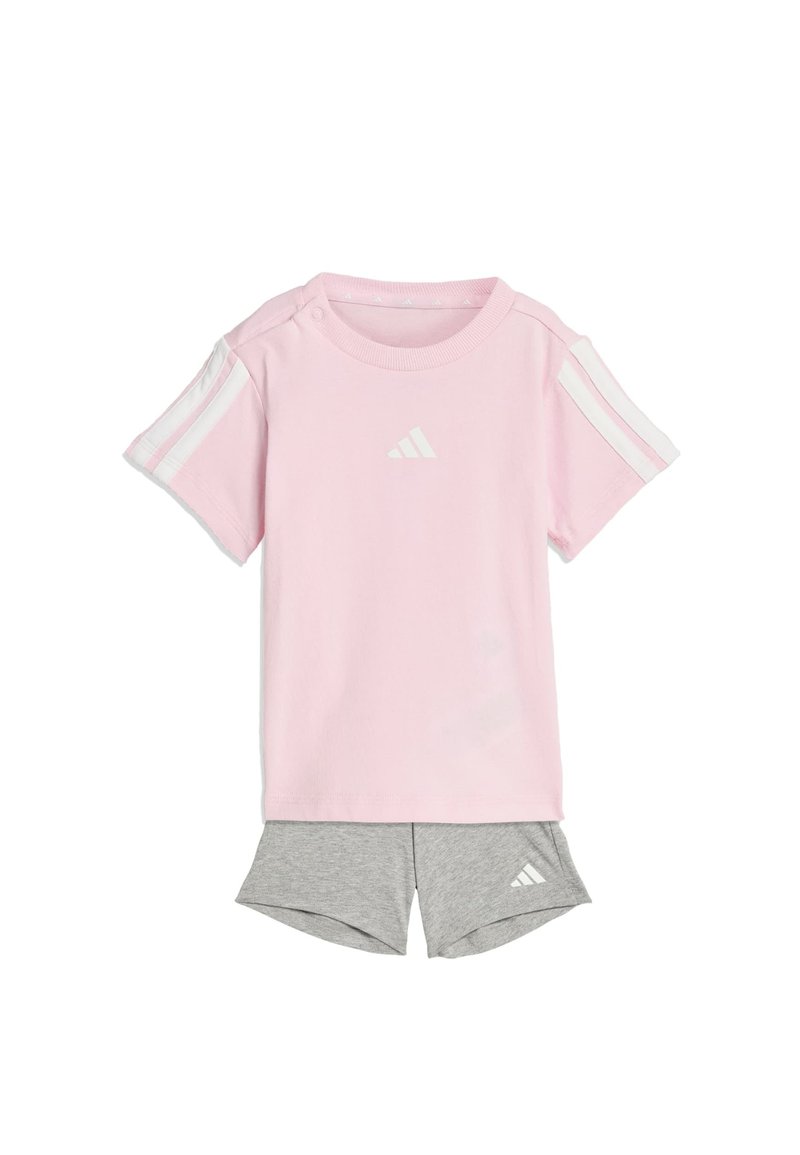 Camiseta de manga corta de color rosa claro con rayas blancas en los hombros y logo; combinada con pantalones cortos deportivos grises con un logo en el dobladillo.