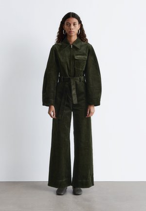 Dunkelgrüner Corduroy-Overall mit einem Kragen, Reißverschluss vorne, weit geschnittenen Hosenbeinen und einem passenden Gürtel. Enthält eine Brusttasche.
