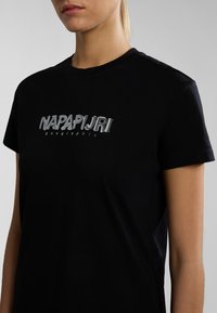 Black cotton t-shirt featuring a silver embroidered "NAPAPIJRI geographic" logo on the chest. Short sleeves, standard crew neck design.