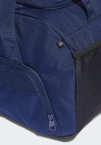 Donkerblauwe stoffen sporttas met een ritscompartiment, mesh accenten en een label "EIND PLASTICAFVAL". Stevige vormgeving en gestructureerd oppervlak.