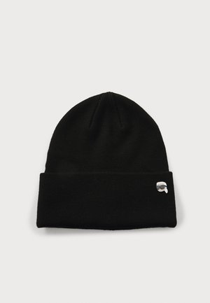 Black knitted beanie hat with a folded cuff and a small embroidered logo featuring a face with sunglasses on the side. Soft texture.