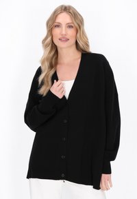 Cardigan negru cu decolteu în V, mâneci lungi și închidere cu buton. Prezintă mansete cu model în relief și o croială lejeră. Textură netedă, tricotată.