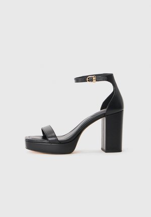 Sandali platform neri con tacco a blocco spesso, realizzati in pelle liscia, design open toe e una cinghia alla caviglia con un accento di fibbia dorata.