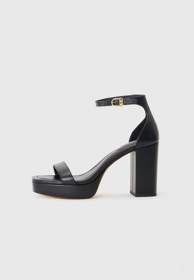 Sandalias de plataforma negras con un grueso tacón cuadrado, material de cuero suave, diseño de puntera abierta y una correa para el tobillo con un acento de hebilla dorada.