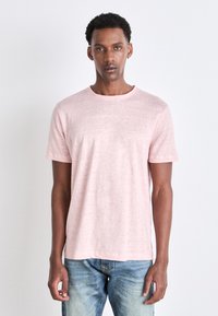 Ljusrosa kortärmad T-shirt tillverkad av ett mjukt, texturerat tyg. Rund halsdesign med en något avslappnad passform.