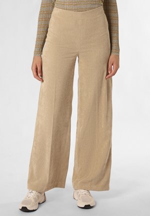 Beige wijduitlopende ribfluwelen broek gedragen met beige en witte sneakers en een gestreept top met lange mouwen, gezien van taille tot voeten.