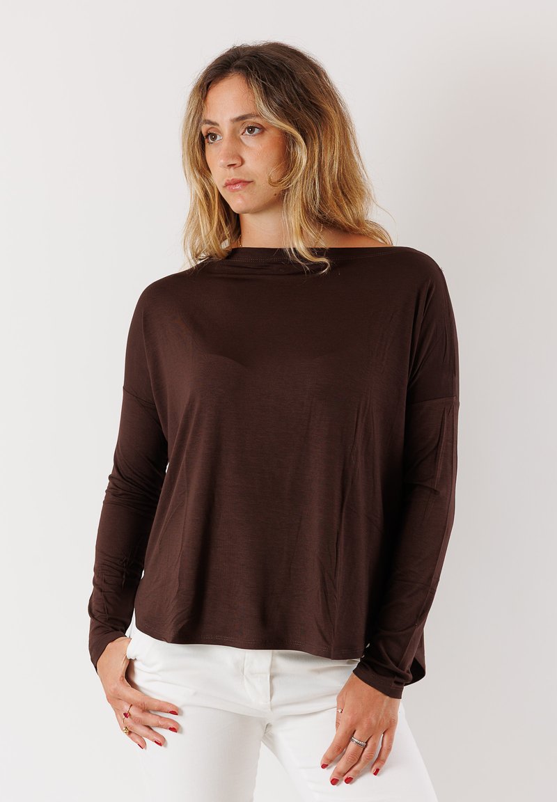 Maglia marrone a maniche lunghe con scollo a barca, realizzata in un tessuto morbido e leggero. Presenta una vestibilità rilassata e polsini arrotolati, abbinata a pantaloni bianchi.