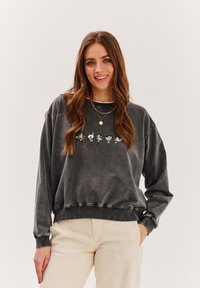 Šedá mikina vyrobená z jemné bavlny, s kulatým výstřihem, dlouhými rukávy a barevným výšivkou kreslených postaviček na přední straně.