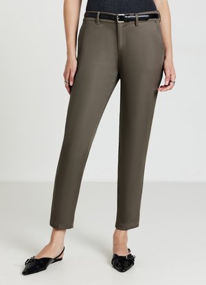 Maßgeschneiderte olivgrüne Hose mit schlankem Schnitt, flachem Bund und subtiler Dehnbarkeit. Kombiniert mit einem schwarzen Leder-Gürtel und spitzen, schwarzen Slingbacks.