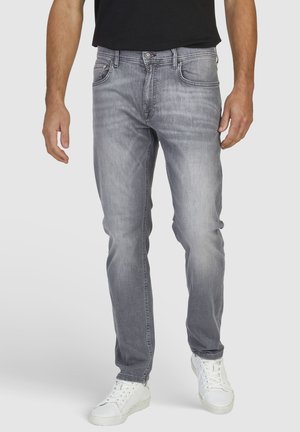 Lichtgrijze jeans met een rechte pasvorm, voorzien van vijf zakken, subtiele vervaging en een knoopsluiting. Draagt met witte sneakers.