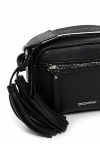 Borsa a tracolla nera realizzata in pelle testurizzata. Presenta una chiusura con zip, hardware in argento e un'accento a nappina sul lato. Nome del marchio visibile.