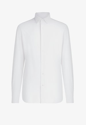 Valge pika varrukaga särk, mis on valmistatud puuvillast, ees nupuga kinni pandud, klassikalise kraega, sirge alumise ääre ja tavalise manseti disainiga.