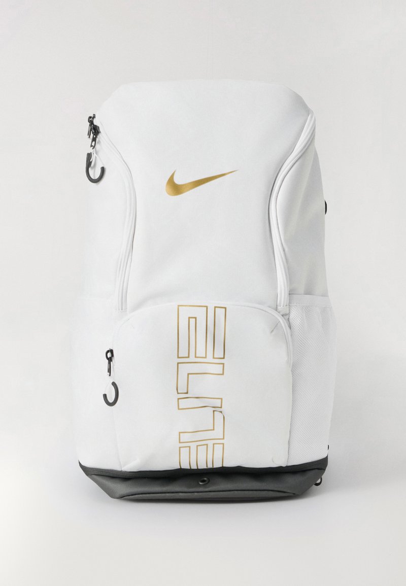 Zaino Nike bianco con logo oro e testo "ELITE", chiusure con zip, tasche laterali in rete e base nera. Texture liscia.