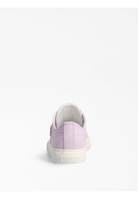Sneaker in tela lavanda con suola in gomma bianca, linguetta posteriore e cuciture visibili. Nome del marchio "GUESS" impresso sul tallone.