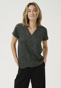 Olijfgroene V-hals t-shirt met een structuur van zebra-strepen, korte mouwen, relaxed fit, en gecombineerd met zwarte broek.