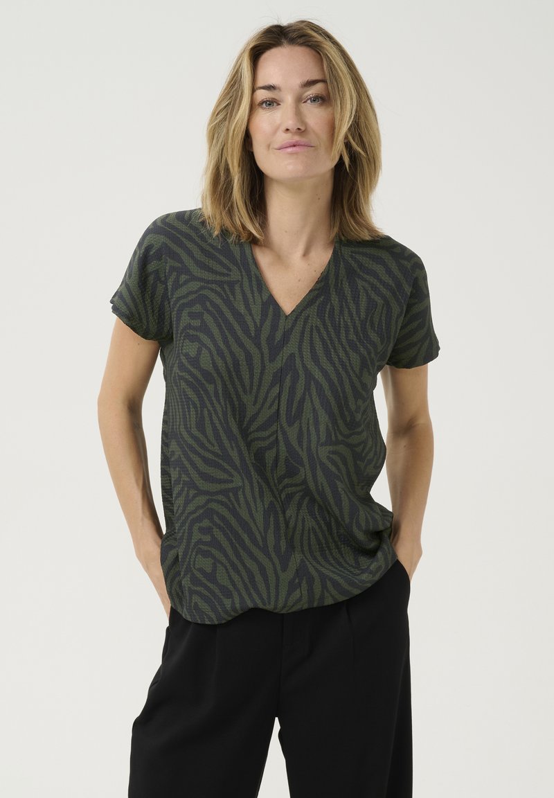 Olijfgroene V-hals t-shirt met een structuur van zebra-strepen, korte mouwen, relaxed fit, en gecombineerd met zwarte broek.