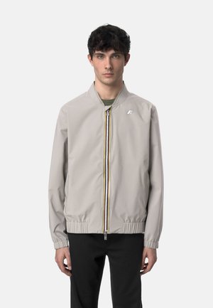 Giacca bomber grigia chiara con zip frontale, colletto a coste, polsini e orlo elasticizzati. Presenta un logo discreto sul petto e dettagli di zip a contrasto.