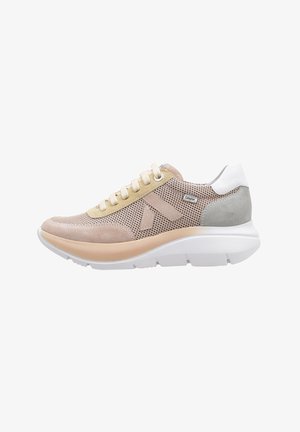 Zapatilla con una parte superior de malla beige, acentos de ante en beige claro y gris, talón blanco y una suela blanca gruesa. Presenta cordones beige.