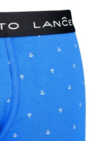 Niebieskie bawełniane bokserki z czarnym pasem w talii, na którym znajduje się biały napis oraz mały biały wzór okrągłych kształtów na całej powierzchni materiału.