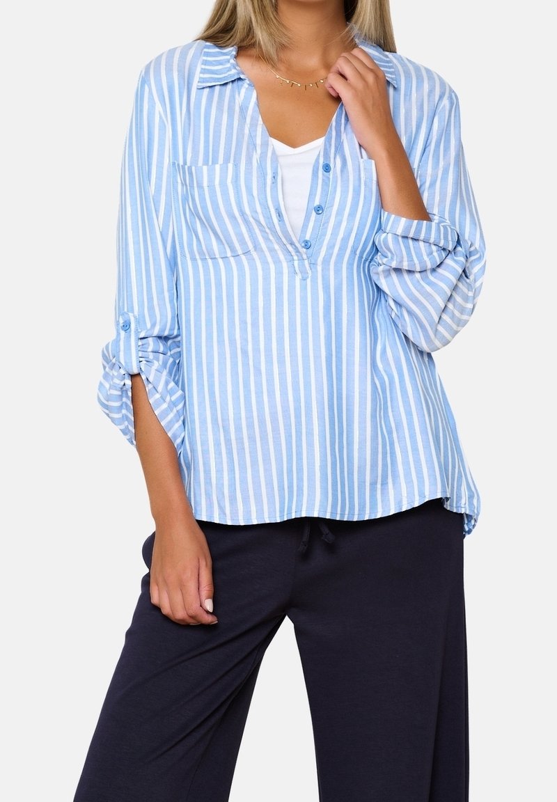 Chemise à manches longues bleu clair et blanche à rayures, avec une coupe décontractée, un col et des manches retroussées. Elle possède une poche poitrine et est fabriquée dans un tissu doux.