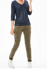 Navy v-neck top with 3/4 sleeves paired with olive cargo pants featuring knee patches and side pockets, complemented by white sneaker shoes.