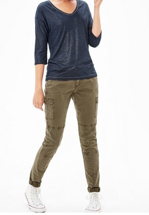 Navy v-neck top with 3/4 sleeves paired with olive cargo pants featuring knee patches and side pockets, complemented by white sneaker shoes.
