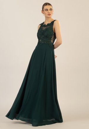 Langes smaragdgrünes Kleid mit einem taillierten Oberteil, das mit floraler Stickerei und transparenten Einsätzen verziert ist, fließender Rock mit einer vollen Silhouette und glatter Textur.