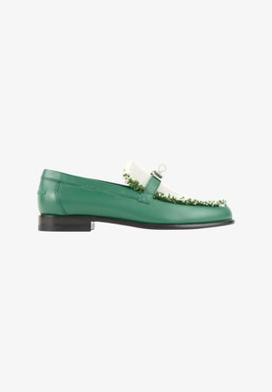 Mocassin vert en cuir avec tissu blanc texturé et détail de franges vertes sur le dessus, semelle noire et décoration anneau argenté.
