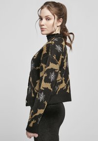 Black knitted sweater with gold and white reindeer patterns, cropped fit, round neckline, buttons on the front, textured fabric.