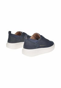 Un paio di sneaker in pelle blu navy con suole spesse bianche, colli imbottiti e il marchio dorato "Alexander Smith" sui lati e sui talloni.
