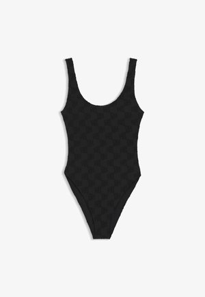 Maillot de bain une pièce noir avec larges bretelles et texture subtile à damier, présenté sur un fond blanc.