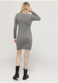 Grey knit sweater dress with long sleeves, fitted shape, and ribbed cuffs, paired with black ankle boots featuring a chunky sole.