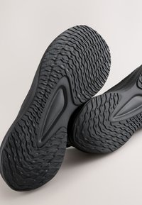 Black athletic shoes with textured, grooved soles. The design features a streamlined shape and rubber material with a lightweight appearance.