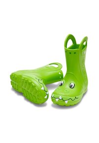 Botas de lluvia de goma verdes con un diseño de cocodrilo, que incluyen ojos, dientes, suelas texturizadas y asas laterales para facilitar su uso.