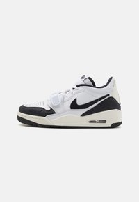 Fehér Nike sportcipő, texturált fekete orral és sarokkal, fűzős záródással és látható légpárnázással a talpban.