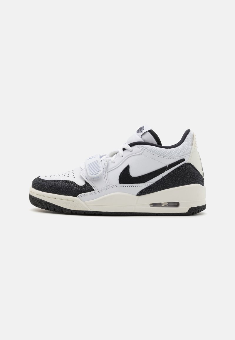 Fehér Nike sportcipő, texturált fekete orral és sarokkal, fűzős záródással és látható légpárnázással a talpban.