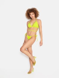 Set di bikini verde neon con top triangolare e spalline regolabili. Presenta un fondo a vita alta abbinato e sandali con tacco trasparente.