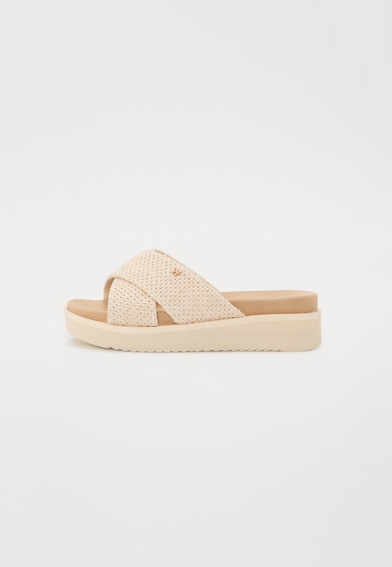 Beiga slidesandaler med en texturerad ovandel som har korsade remmar, en vadderad sula och en kraftig avvikande vit sula.