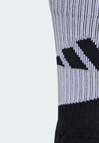 Chaussette de sport noir et blanc avec texture à côtes, comportant un motif de logo noir et des rayures blanches contrastantes en haut.