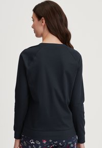 Marineblauwe sweatshirt met een ronde hals, raglanmouwen en een ribgebreide zoom. De stof is een glad, rekbaar materiaal. Geen zichtbare logo's of patronen.