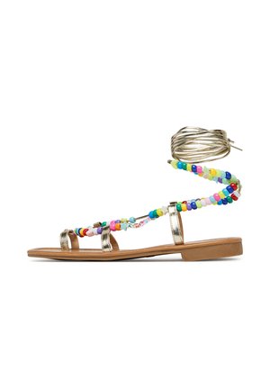 Gold metallic flat sandal with colorful bead accents. Features three straps and a wrap-around ankle tie. Smooth flat sole.