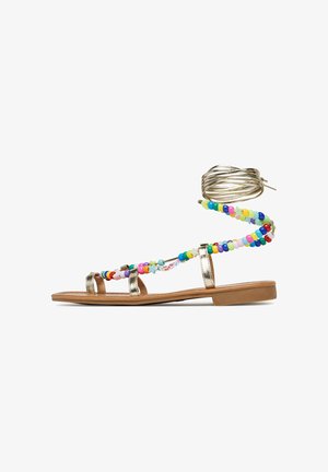 Gold metallic flat sandal with colorful bead accents. Features three straps and a wrap-around ankle tie. Smooth flat sole.