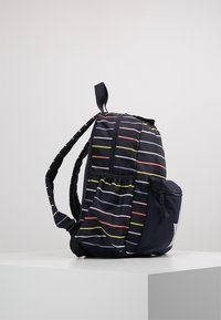 Mochila negra con rayas horizontales de colores. Incluye correas acolchadas, un bolsillo lateral y un cierre de cremallera. Diseño compacto y ligero.