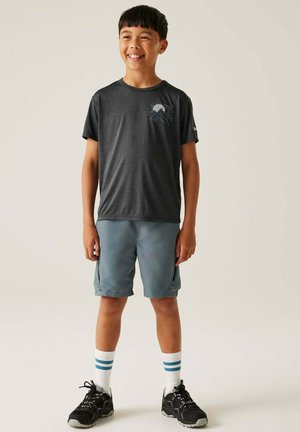 Graues Sport-T-Shirt mit Berggrafik, kombiniert mit blauen Cargo-Shorts, weißen Socken mit blauen Streifen und schwarzen Sneakers.